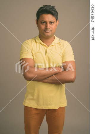 Portrait of young handsome Indian man against plain studio background 74979450