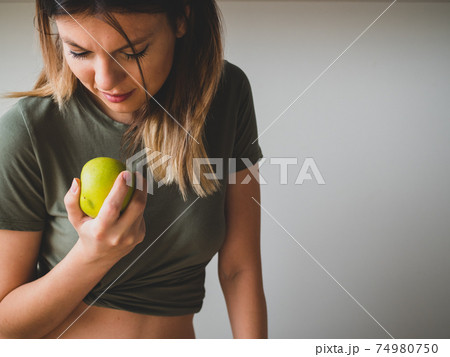 Beautiful sporty woman want to bite a green apple in hand. Healthy food Beautiful sporty woman want to bite a green apple in hand. Healthy food 74980750