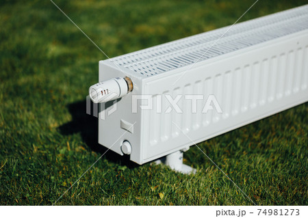 radiator on green lawn, ecological heating concept 74981273