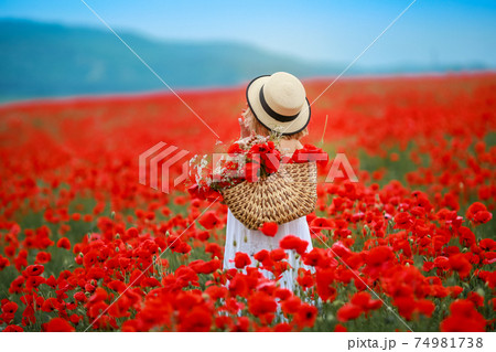 Rear view of a woman in a field with red poppies 74981738