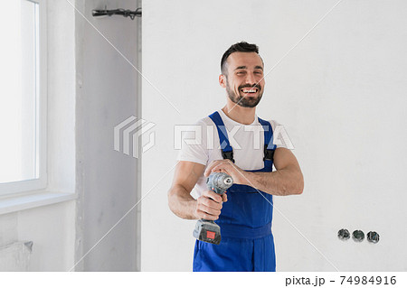 Builder posing with a drill in his hands and smiling Builder posing with a drill in his hands and smiling 74984916
