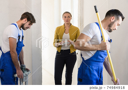 Workers cover the wall with mortar with a roller Workers cover the wall with mortar with a roller 74984918