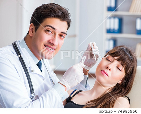 Doctor checking patients ear during medical examination Doctor checking patients ear during medical examination 74985960