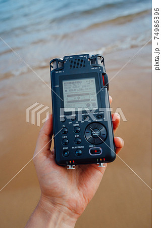 portable audio recorder in hand recording ambient sounds of sea portable audio recorder in hand recording ambient sounds of sea 74986396