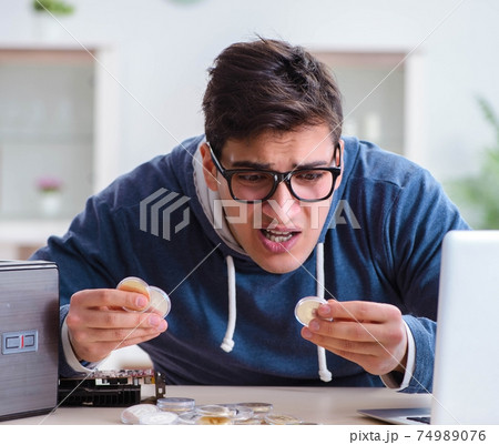 Young man mining bitcoins at home Young man mining bitcoins at home 74989076