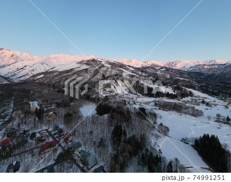 美しい白馬三山のモルゲンロートと八方尾根スキー場のパノラマ写真　長野県白馬村（ドローンによる空撮） 74991251