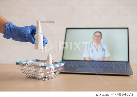 A friendly doctor conducts an online consultation on a laptop. A gloved pharmacist puts medicine into a mini shopping cart. The concept of distance medicine. Order drugs online. A friendly doctor conducts an online consultation on a laptop. A gloved pharmacist puts medicine into a mini shopping cart. The concept of distance medicine. Order drugs online. 74994673