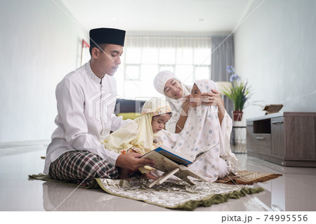 happy muslim family with children reading quran and pray together happy muslim family with children reading quran and pray together 74995556