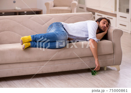 Young man drinking alcohol at home Young man drinking alcohol at home 75000861