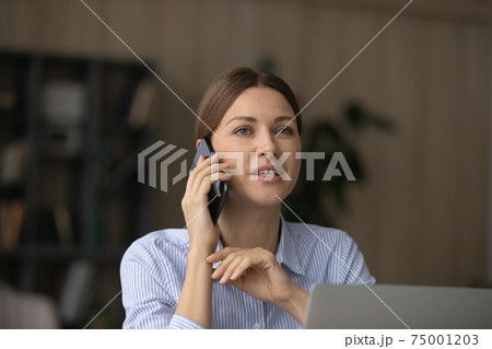 Caucasian woman work on computer talk on smartphone Caucasian woman work on computer talk on smartphone 75001203