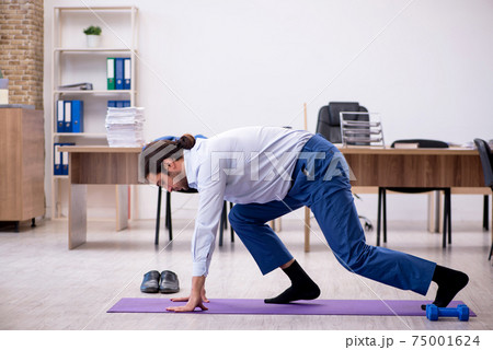 Young male employee doing sport exercises during break Young male employee doing sport exercises during break 75001624