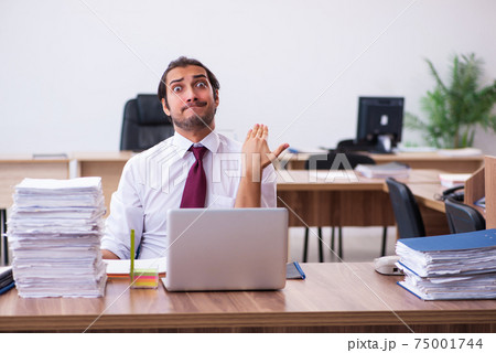 Young male employee unhappy with excessive work in the office 75001744
