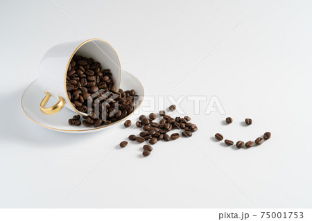 白いカップに入ったコーヒー豆が溢れてしまってニッコリ 75001753