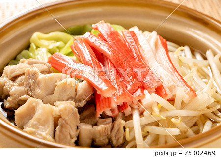 一人前サイズの小さな土鍋に入れられた、かにかまぼこと鶏肉の鍋。 一人前サイズの小さな土鍋に入れられた、かにかまぼこと鶏肉の鍋。 75002469