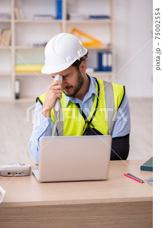Young arm injured male architect working in the office Young arm injured male architect working in the office 75002554