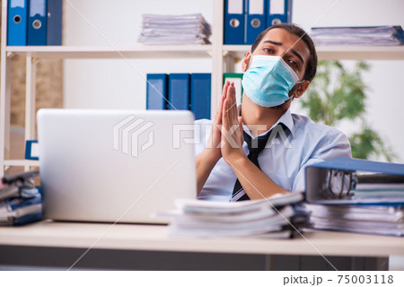 Young male employee working in the office during pandemic 75003118