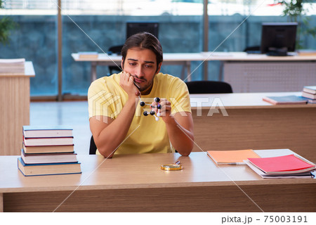 Young male student physicist preparing for exams in the classroom 75003191