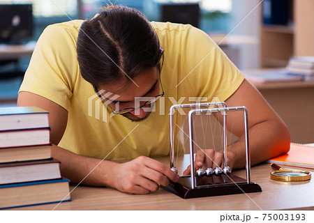 Young male student physicist preparing for exams in the classroom 75003193