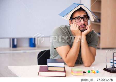 Young male student preparing for exams in the classroom Young male student preparing for exams in the classroom 75003276