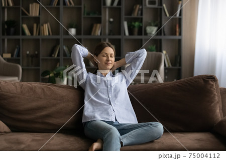 Calm young Caucasian woman relax on couch at home Calm young Caucasian woman relax on couch at home 75004112