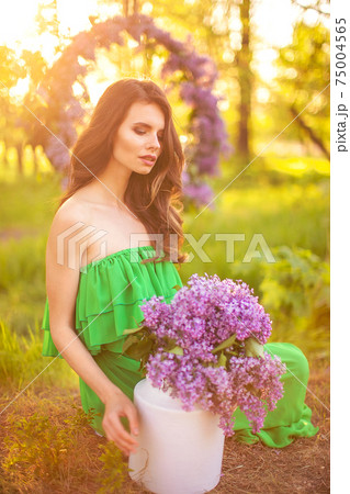 attractive woman in green dress posing near lilac flower 75004565