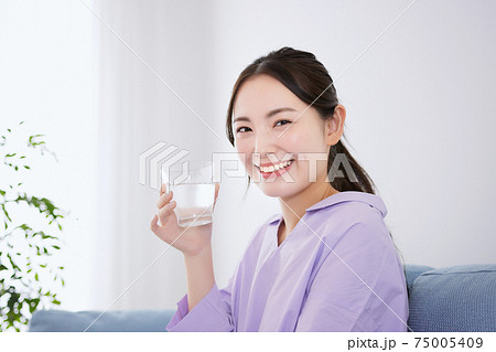 ソファで水を飲む若い女性 ソファで水を飲む若い女性 75005409