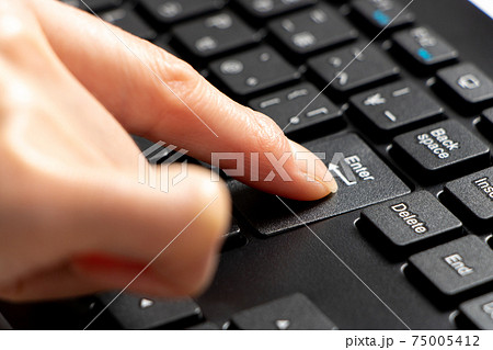 キーボードのエンターキーを押す指 の写真素材