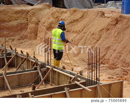 KUALA LUMPUR, MALAYSIA -JULY 30, 2020: Construction workers mixing and spraying the anti termite chemical treatment to the soil at the construction site.  75005695