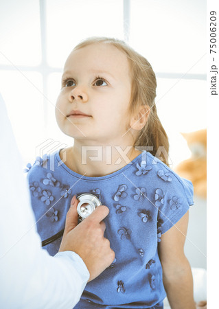 Doctor examining a little girl by stethoscope. Happy smiling child patient at usual medical inspection. Medicine and healthcare concepts Doctor examining a little girl by stethoscope. Happy smiling child patient at usual medical inspection. Medicine and healthcare concepts 75006209