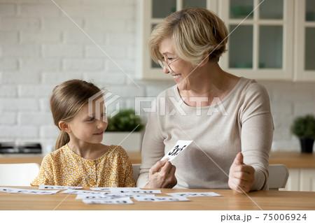 Aged woman teacher study math with pupil girl using cards Aged woman teacher study math with pupil girl using cards 75006924