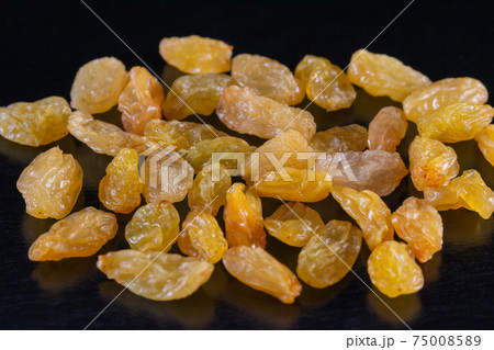 Yellow raisins on a black background close-up. Yellow raisins on a black background close-up. 75008589