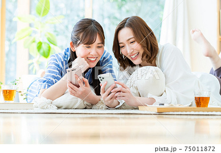 友達とスマホを見る若い女性の写真素材