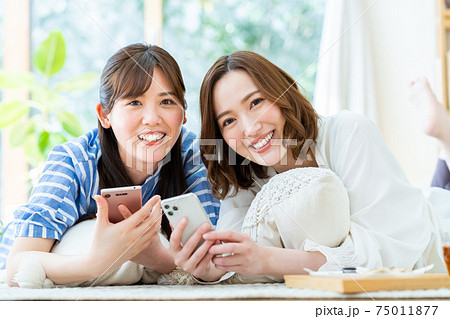 友達とスマホを見る若い女性の写真素材