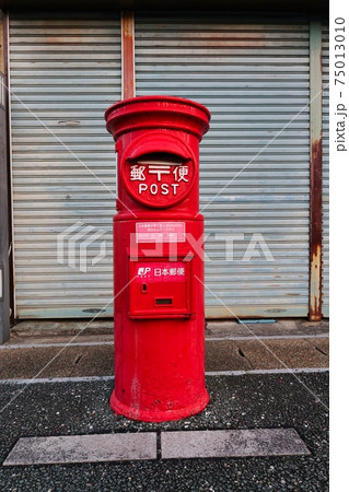 シャッターの前の古いタイプの赤い郵便ポストの写真素材 [75013010