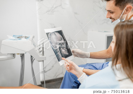 Dentist showing x-ray of a skull for young patient 75013618