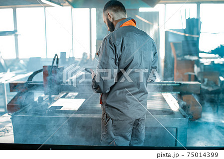 Heavy industry worker controlling the process of metal cutting Heavy industry worker controlling the process of metal cutting 75014399