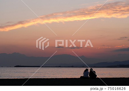 海辺で夕焼けを見つめるふたり 海辺で夕焼けを見つめるふたり 75016626