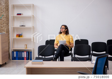 Young male student waiting for teacher in the classroom 75018000