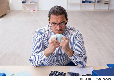 Young male bookkeeper calculating tax payments in the office Young male bookkeeper calculating tax payments in the office 75019289
