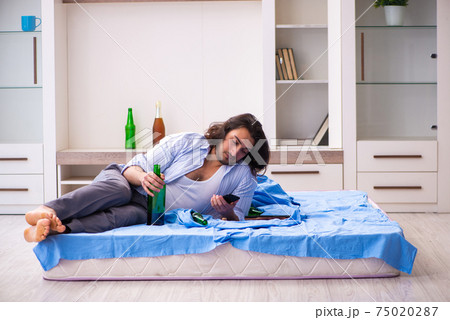Young male alcoholic in the bedroom Young male alcoholic in the bedroom 75020287