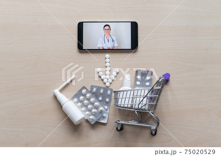 Friendly female doctor on a smartphone screen prescribes treatment. Online medicine. Mini trolley with pills. Remote consultation. Mobile application pharmacy. Friendly female doctor on a smartphone screen prescribes treatment. Online medicine. Mini trolley with pills. Remote consultation. Mobile application pharmacy. 75020529