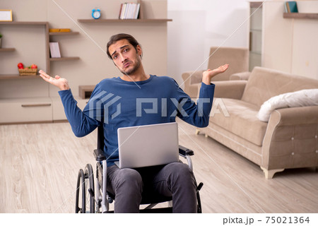 Young man in wheel-chair suffering at home Young man in wheel-chair suffering at home 75021364