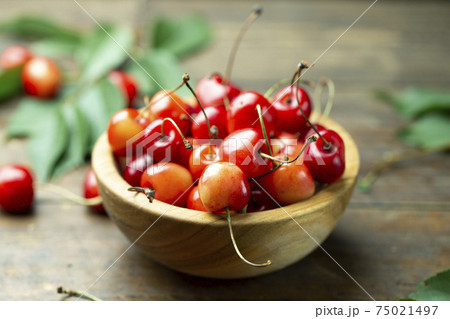 Fresh sweet cherries with leaves in a wooden plate Fresh sweet cherries with leaves in a wooden plate 75021497