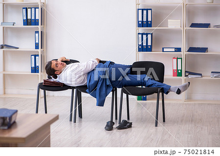 Young male employee sleeping in the office on chairs Young male employee sleeping in the office on chairs 75021814