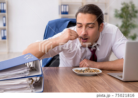 Hungry male employee eating buckwheat during break Hungry male employee eating buckwheat during break 75021816