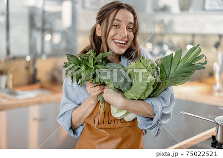 Woman with fresh green vegetables on the kitchen Woman with fresh green vegetables on the kitchen 75022521