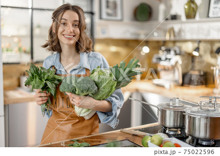 Woman with fresh green vegetables on the kitchen 75022596