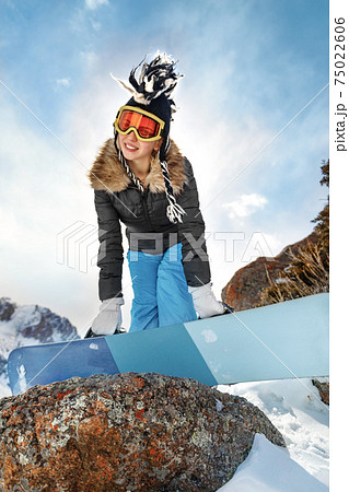 Portrait of beautiful young woman snowboarder standing on top of the mountain background. Portrait of beautiful young woman snowboarder standing on top of the mountain background. 75022606