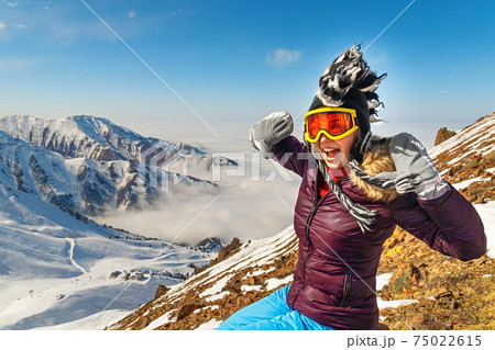 Emotional traveler young woman with windy hair smiling, sitting on top of sunny mountains. Funny woman in mohawk hat. Emotional traveler young woman with windy hair smiling, sitting on top of sunny mountains. Funny woman in mohawk hat. 75022615