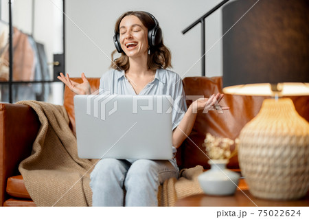 Woman working with laptop and headphones from home Woman working with laptop and headphones from home 75022624